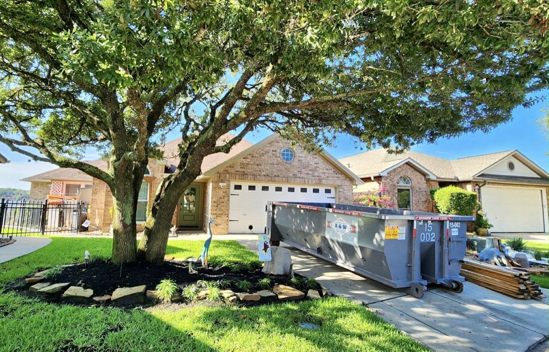A&W branded 15 yard dumpster in a suburban driveway during a deck rebuild